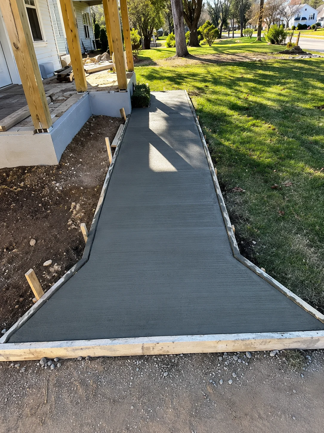 Finished concrete walkway with metal edging, smooth gray surface, wooden framing visible