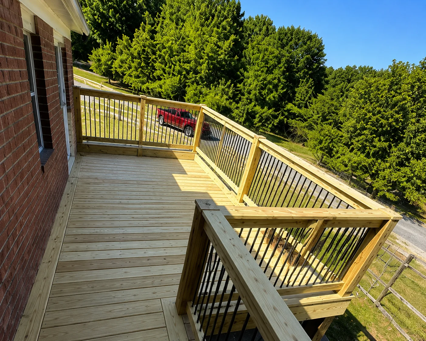 Two-level pressure-treated wood deck with black metal spindle railings and composite decking